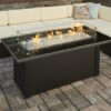 Monte Carlo fire table with flames on by a patio sectional.
