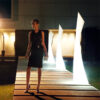 The wing lamp by Vondom lit up with a woman standing next to them.