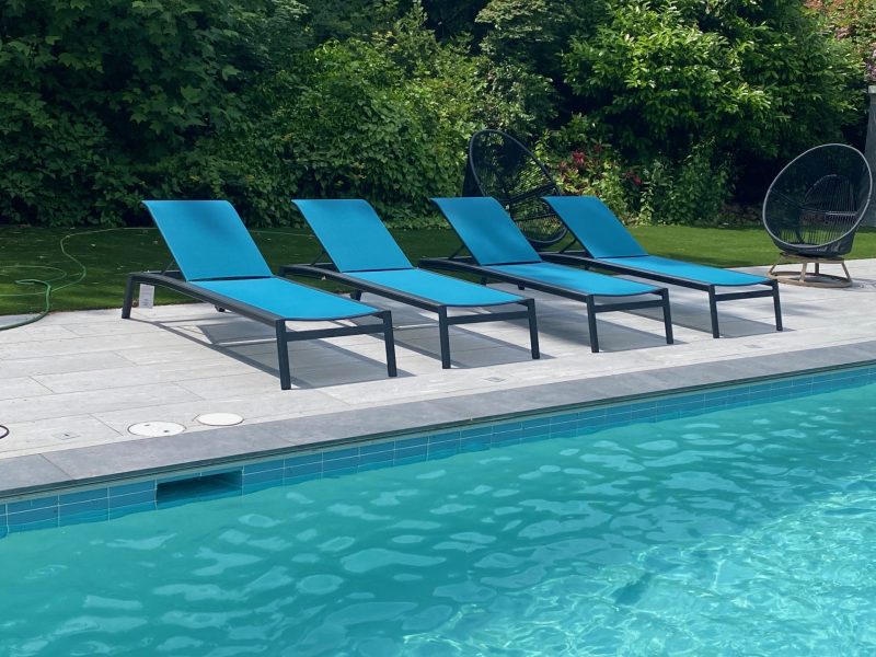 Lyon loungers in peacock next to a pool.